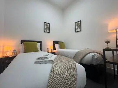 two beds in a room with two lamps and towels on them at Squarezzz - Group Accommodation in Edinburgh