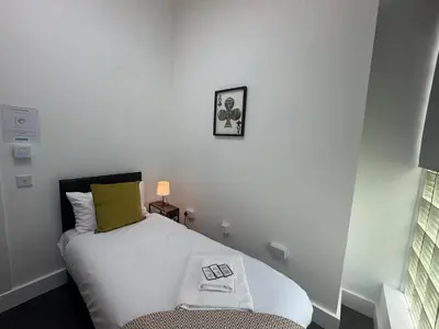 a small bedroom with a bed and a chair at Squarezzz - Group Accommodation in Edinburgh