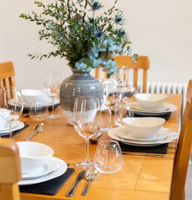 a wooden table with glasses and a vase with flowers at The Dower House at Solsgirth Home Farm in Dollar
