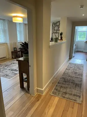 an empty living room with a table and a rug at The Butler's Flat at Solsgirth Home Farm in Dollar
