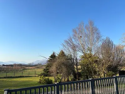 a bench in a field with trees and a fence at The Loch Lomond But n Ben in Gartocharn