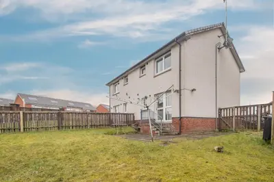 a white house with a fence in a field at Ideal Contractor Stay 2-Bed Near Glasgow Fort in Garthamlock