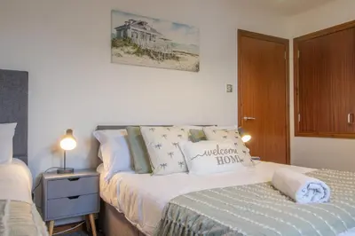 a bedroom with a bed and a nightstand next to a bed at Ideal Contractor Stay 2-Bed Near Glasgow Fort in Garthamlock
