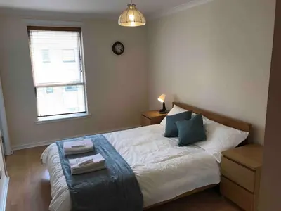 a bedroom with a bed with a table and a window at Apartment in Heart of West End- Parking Space- Spacious- Near Glasgow University and Kelvingrove Art Gallery in Glasgow