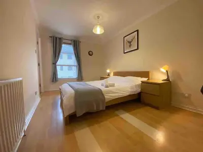a bedroom with a bed and a nightstand and a window at Apartment in Heart of West End- Parking Space- Spacious- Near Glasgow University and Kelvingrove Art Gallery in Glasgow