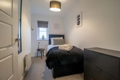 a small bedroom with a bed and a dresser at Lendrick House-Spacious 3 Bed House in Falkirk in Polmont