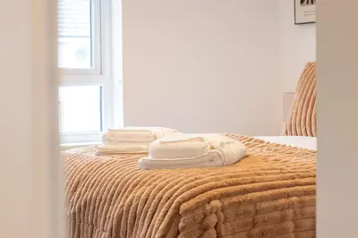 a bed with towels on top of it with a window at Lendrick House-Spacious 3 Bed House in Falkirk in Polmont
