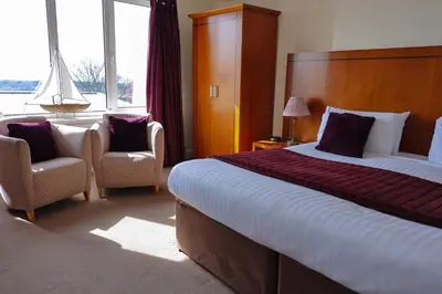 a hotel room with a large bed and two chairs at Highgrove House Hotel in Loans