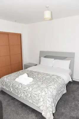 a bedroom with a large bed with white sheets at Glasgow Hydro Apt with Great Views in Glasgow