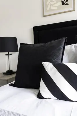 a bed with black and white pillows and a black headboard at Charlotte Apartment in Glasgow