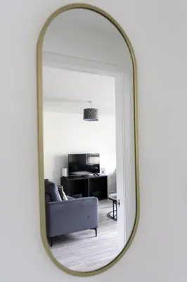 a mirror reflecting a living room with a couch at Charlotte Apartment in Glasgow