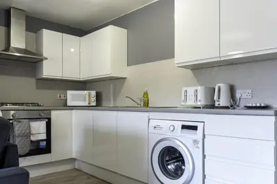 a white kitchen with a washing machine in it at Charlotte Apartment in Glasgow