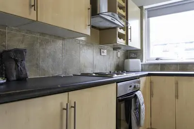 a kitchen with wooden cabinets and a stove top oven at Riverview House in Glasgow