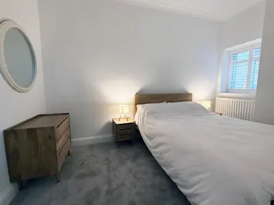 a bedroom with a bed and a dresser and a mirror at Bay View Cottage in Fairlie