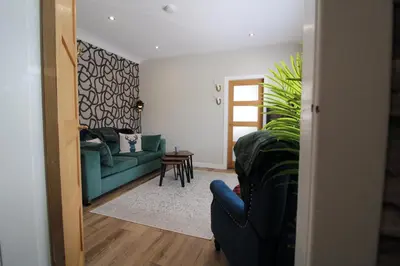 a living room with a green couch and a table at Links Cottage, Prestwick in Prestwick