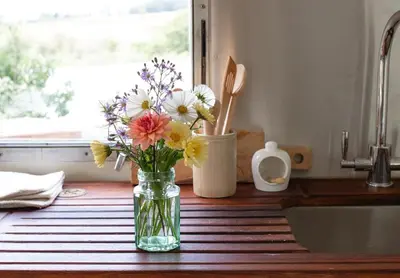 a vase filled with flowers sitting on a kitchen counter at Luxury Airstream Getaway with Sauna and Hot Tub in Gartness
