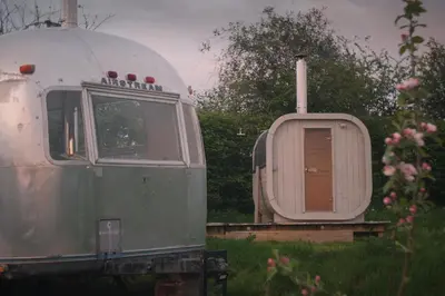 an old trailer with a door in the grass at Luxury Airstream Getaway with Sauna and Hot Tub in Gartness