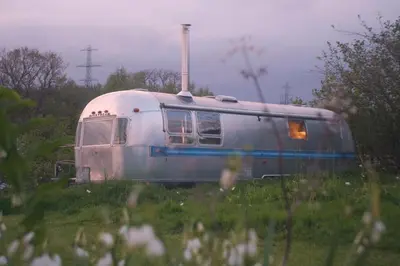 a train sitting on the tracks in a field at Luxury Airstream Getaway with Sauna and Hot Tub in Gartness