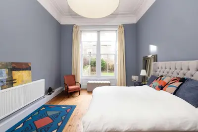 a bedroom with a large bed and a window at JOIVY Spacious 2-Bedroom Ground Floor Flat in Edinburgh