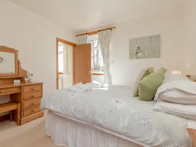 a bedroom with a bed and a dresser and a window at Holiday Home Doonans Cottage by Interhome in Straiton