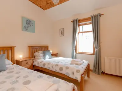 a bedroom with two beds and a window at Holiday Home Doonans Cottage by Interhome in Straiton