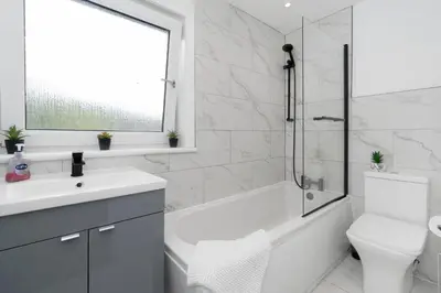 a bathroom with a white tub and a toilet and a sink at Vacant Nests The Livingston Retreat Wi-Fi in Uphall