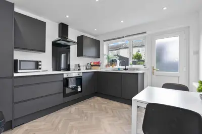 a kitchen with black and white appliances and a table at Vacant Nests The Livingston Retreat Wi-Fi in Uphall