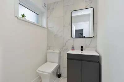 a bathroom with a toilet and a sink and a mirror at Vacant Nests The Livingston Retreat Wi-Fi in Uphall