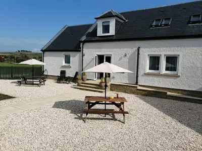 a table with an umbrella in front of a house at East Laigh Gree Bed and Breakfast in Burnhouse