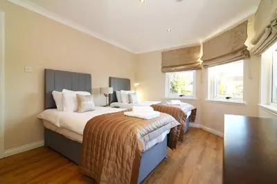 a bedroom with two beds and two windows at Signature - Cross House in Lanark