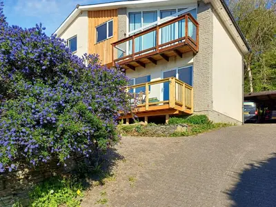 a house with a balcony and purple flowers at Ardtornish Apartment in Tayvallich