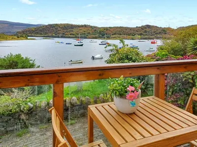 a porch with a table and a view of a lake at Ardtornish Apartment in Tayvallich