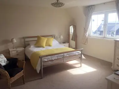 a bedroom with a bed with yellow pillows and a window at Stonewater House Vegan Bed and Breakfast in Lamlash