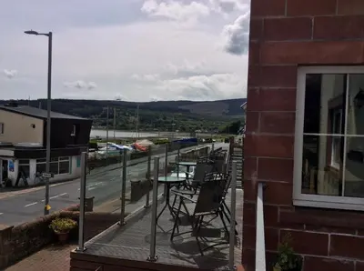 a balcony with chairs and a view of a street at Stonewater House Vegan Bed and Breakfast in Lamlash