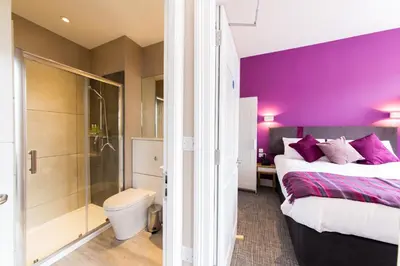 a bedroom with purple walls and a bed and a shower at The Spires Serviced Apartments Edinburgh in Edinburgh