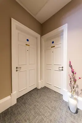 a hallway with two doors and a vase with flowers at The Spires Serviced Apartments Edinburgh in Edinburgh