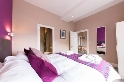 a bedroom with a large white bed with purple pillows at The Spires Serviced Apartments Edinburgh in Edinburgh
