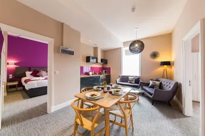 a living room with a table and a bedroom at The Spires Serviced Apartments Edinburgh in Edinburgh