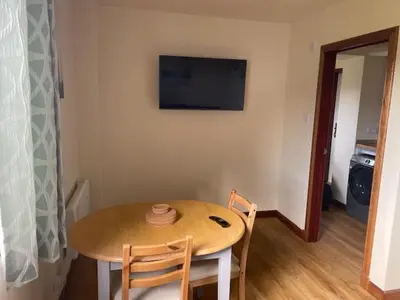 a dining room table with two chairs and a television on the wall at The Roost in Appin