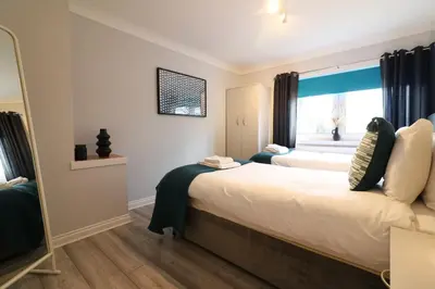 a bedroom with two beds and a window at Signature - Drumvale House in Chryston