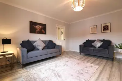 a living room with two couches and a rug at Signature - Drumvale House in Chryston