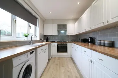 a kitchen with white cabinets and a dishwasher at Signature - Drumvale House in Chryston
