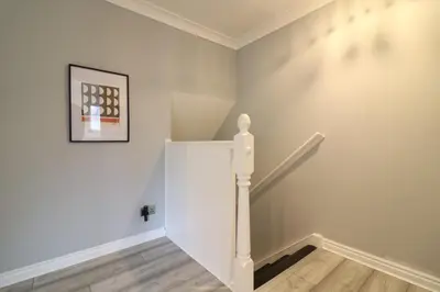 a staircase in a white room with a picture on the wall at Signature - Drumvale House in Chryston