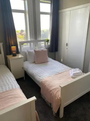 a bedroom with two beds and two windows at Glen Mhor - Beautiful two bedroom apartment Dunfermline in Townhill