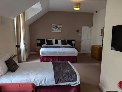 a hotel room with two beds and a flat screen tv at Gordon Arms Hotel in West Linton