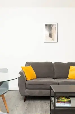 a living room with a gray couch with yellow pillows at Vacant Nests The Milton Dunfermline Parking in Dunfermline