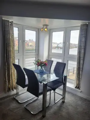 a dining room with a glass table and chairs and windows at River Ayr View-Coorie Doon Stays in Ayr