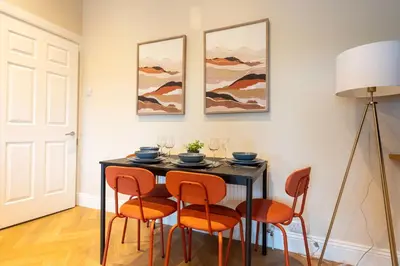 a dining room with a black table and orange chairs at Station Road Stays in Hartwood