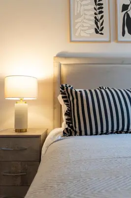 a bed with a black and white pillow and a lamp at Station Road Stays in Hartwood