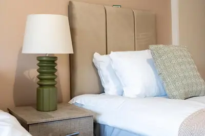 a green lamp on a night stand next to a bed at Station Road Stays in Hartwood